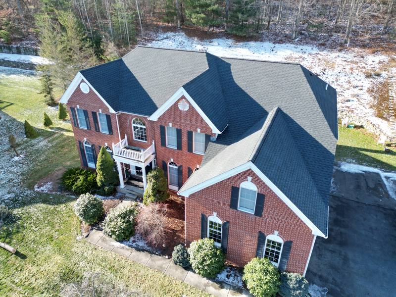 Brick colonial with a dark shingle roof in winter