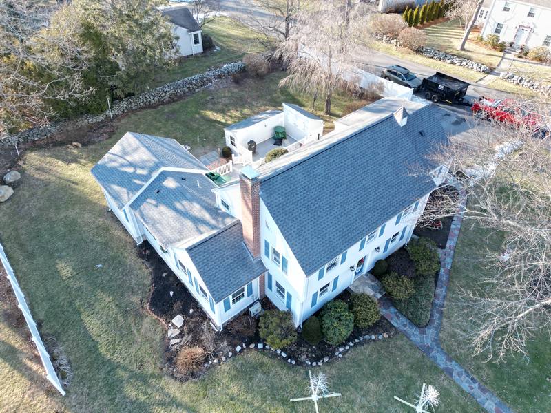 White colonial with a dark shingle roof and chimney