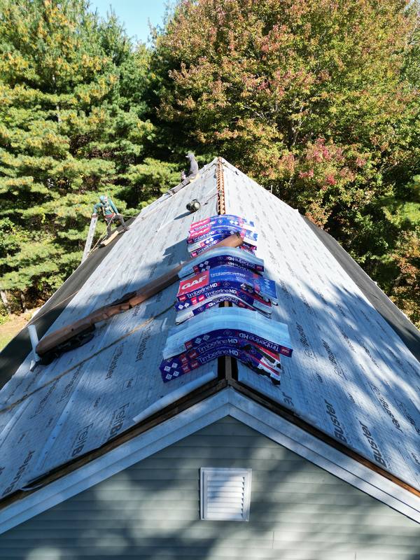 GAF shingle bundles staged on the ridge of a roof being replaced